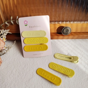 Dettaglio di fermagli per capelli gialli sfumati opachi con smile e scritte stampate