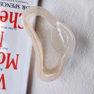 Detailed view of the creamy translucent resin hair claw with a fluid wavy design