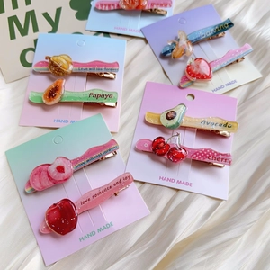 Close-up of glitter fruit hair clips set on pastel cardstock over silk background