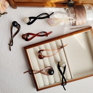 Detail of four matte resin banana hair clips with elegant marble pattern pearl beads