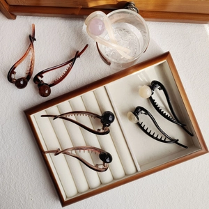Close-up of elegant coffee-toned hair claws with large pearl accents in various colors