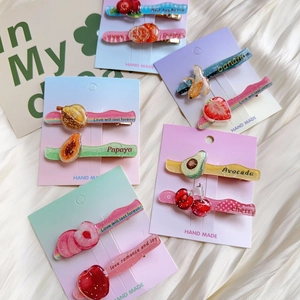 Close-up of glittery acrylic fruit hair clips with strawberry and avocado patterns