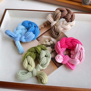 Set of four colorful woven high-elastic hair ties in blue green and pink on a tray