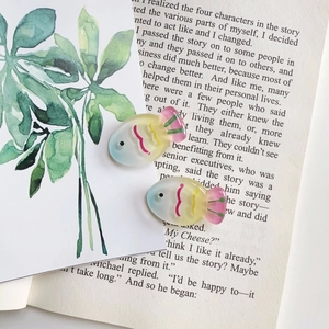 Detail of colorful gradient fish resin hair accessories on a book for DIY projects