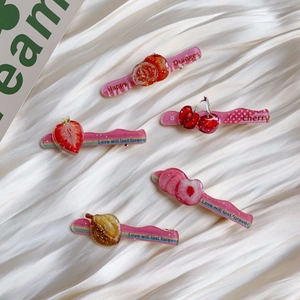 Detailed close-up of 5-piece glitter acrylic fruit hair clips on white silk