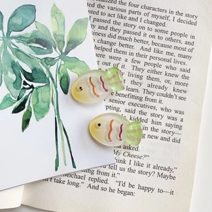 Detail view of two gradient fish-shaped hair clips on a decorative background
