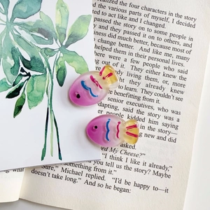 Macro shot of colorful gradient fish resin hair accessories on a decorative book
