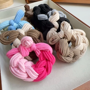 Close-up of colorful braided elastic hair ties in a neutral beige display tray