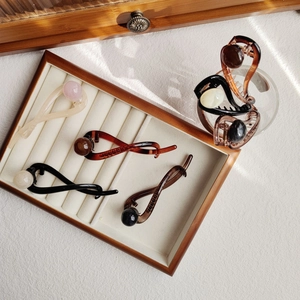 Close-up of twist banana hair clips with pearl beads displayed on a wooden tray