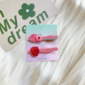 Close-up of glittery cherry and peach acrylic hair clips on a handmade card display