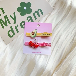 Detail view of glitter acrylic fruit hair clips featuring avocado and cherry patterns