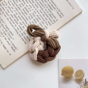 Detail of color-block woven corduroy hair tie with bow shape on white desktop