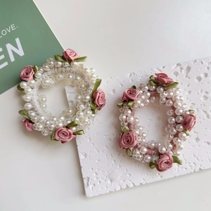 Nahaufnahme von elegantem Perlen-Haargummi mit rosa Stoffrosen und elastischem Gummiband