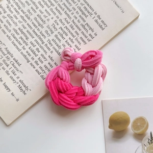 Detailed view of a pink woven hair tie with a bow on top of an open book
