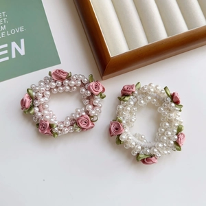 Detailansicht der rosa Seidenrosen und weißen Perlen auf elastischen Haargummis