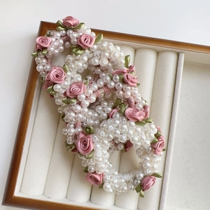Eleganter weißer Perlenhaargummi mit rosa Satinrosen und grünen Blättern in Holzbox