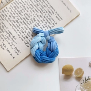 Detail of blue gradient braided scrunchie made of ribbed corduroy on an open book