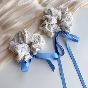 Detail of sea salt blue floral scrunchies with long ribbons on soft pleated background