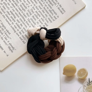 Detailed macro view of high-elasticity braided hair tie on vintage book with lemon accents