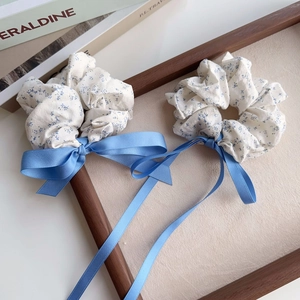 Close-up of blue floral scrunchies with long satin ribbons in a wooden tray