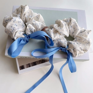 Detailed view of floral scrunchies with long blue silk ribbons on a fashion magazine