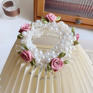 Detail von rosa Stoffrosen und weißen Kunstperlen auf einem flexiblen elastischen Haargummi