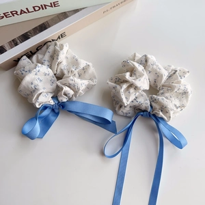 Detail view of blue floral scrunchies with long silk ribbons on a lifestyle background