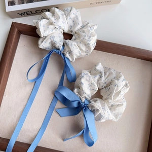 Detail of blue floral scrunchie set with long silk ribbons on a vintage wooden frame