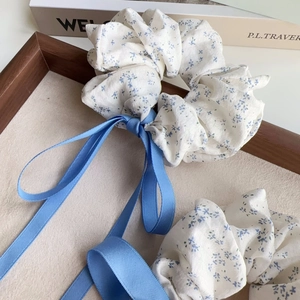 Close-up of sea salt blue floral scrunchies with long satin ribbons in a wooden tray