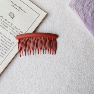 Macro detail of a 17-tooth matte brick red hair side comb with ergonomic curved design