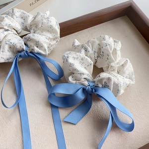 Floral scrunchies with blue satin ribbons in a wooden tray for elegant hair styling