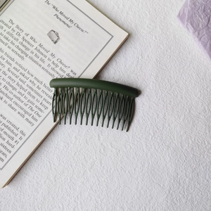 Macro detail of a dark green matte hair insert comb for styling and fixing hair