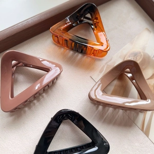 Detailed view of four colorful geometric triangle hair claw clips in various elegant shades
