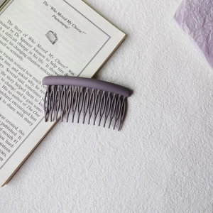Close-up of a purple matte hair comb clip featuring smooth curved lines and dense teeth