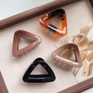 Set of four minimalist triangular hair claw clips in amber, pink, cream, and black colors