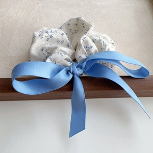 Detail of sea salt blue floral scrunchie with a large satin ribbon bow on wood frame