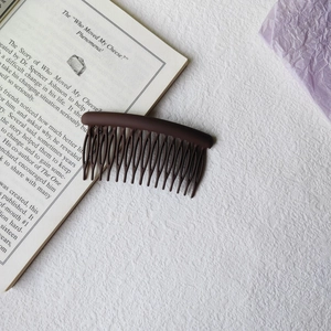 Close-up of a matte dark brown 17-tooth hair side comb for fixing loose hair and bangs