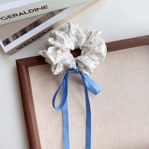 Detail of blue floral scrunchie with silky ribbon bow displayed on a wooden tray