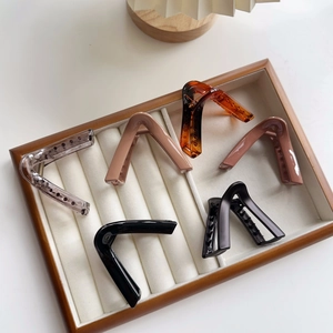 Collection of large triangular hair claw clips in various colors displayed on a tray