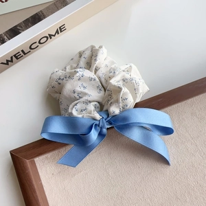 Detailed macro of sea salt blue floral scrunchie with a ribbon bow on wooden frame