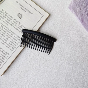 Detail view of a matte black curved hair comb placed on an open book for styling
