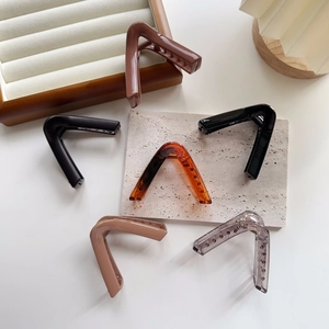 Flat lay of minimalist V-shaped large hair claws in six glossy resin colors on stone plate