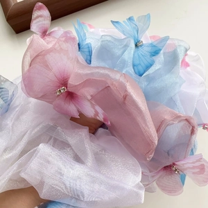 Détail d'un chouchou en organza avec papillons 3D et strass brillants ton pastel féerique