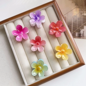 Close-up of 6 colorful acrylic flower hair claws displayed in a velvet jewelry box