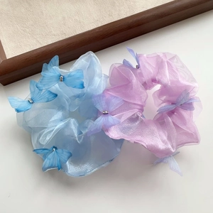 Détail de chouchous en organza bleu clair et violet avec ornements papillon 3D délicats