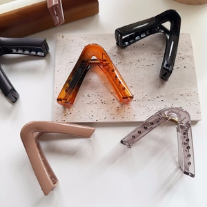 Close-up of five V-shaped large hair claw clips in amber, black, pink and grey colors