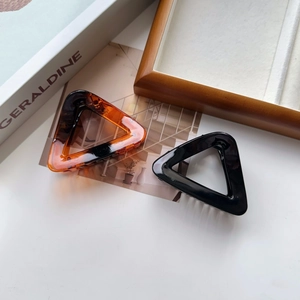 Close-up of large triangle hair claws in amber and black finish with metal springs