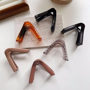 Detail view of large geometric V-shaped hair claws in multiple colors and textures