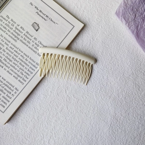 Cream-colored wave tooth hair comb accessory on an open book with soft lighting