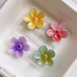 Detailed view of four colorful acrylic flower hair claws in yellow, pink, purple, and green
